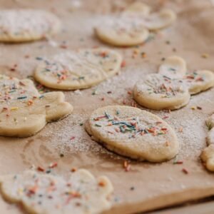 Close-up of raw cookies with sprinkles on baking parchment, ready to be baked.